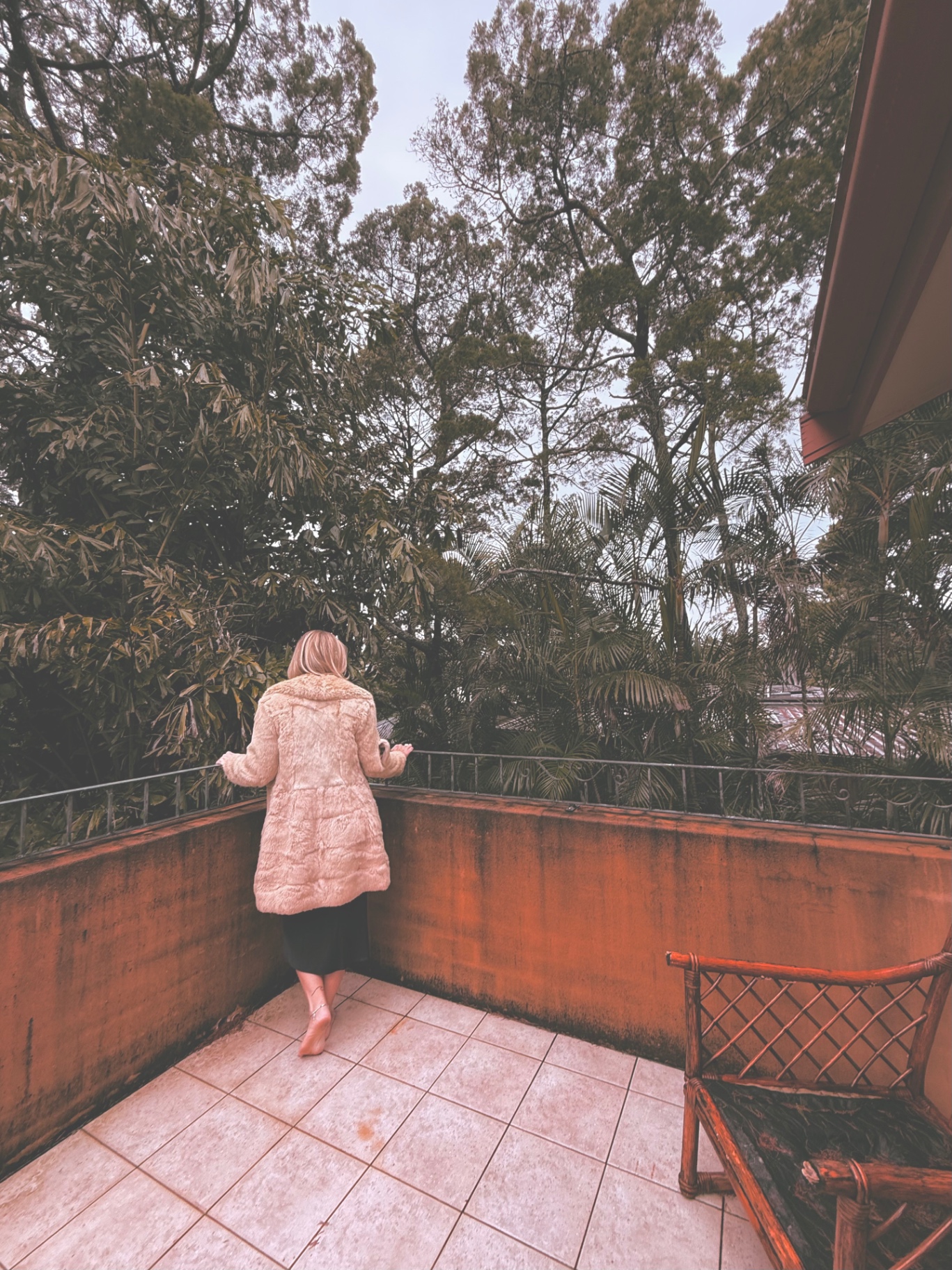 Lauren Jane standing on a balcony surrounded by trees