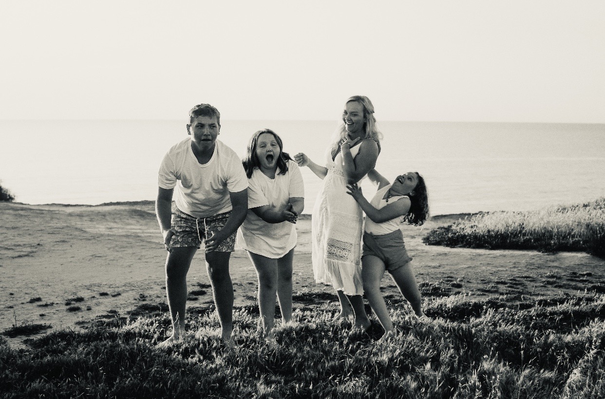 Lauren and her three children laughing together near the coast